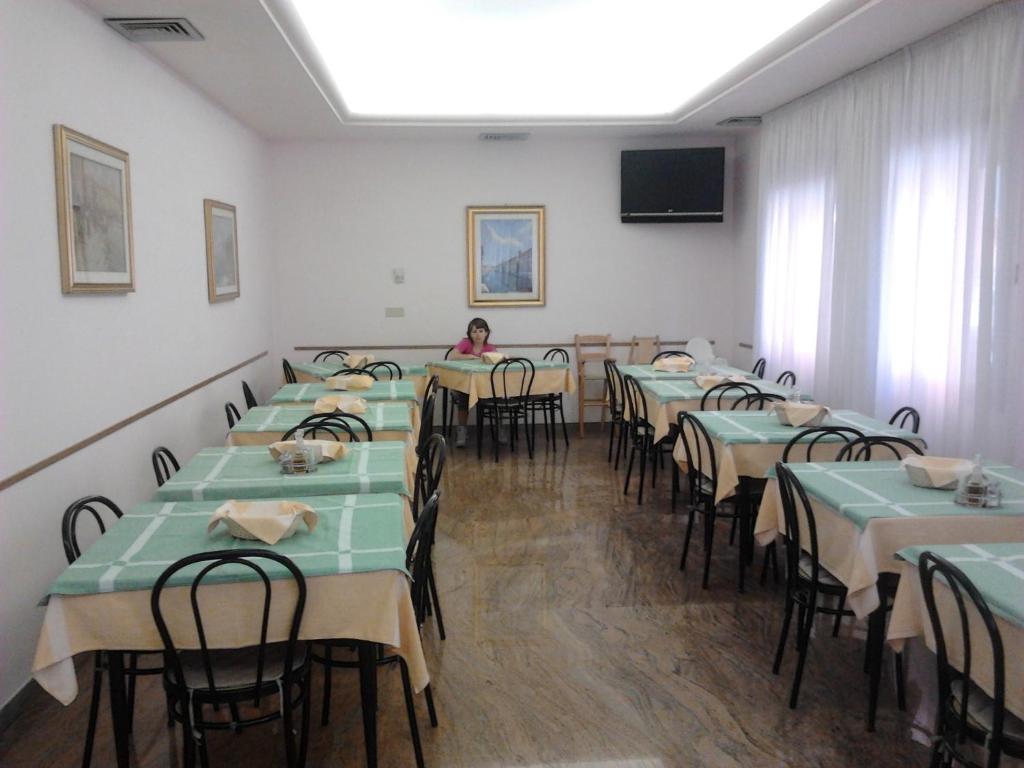 une chambre avec des tables et des chaises et une femme y assise dans l'établissement Hotel Nuova Doel, à Sottomarina