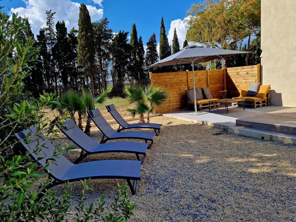 - une rangée de chaises et un parasol dans la cour dans l'établissement Domaine de Mérins, 10 couchages avec piscine, face à la rivière, à 4km de la plage, à Fleury