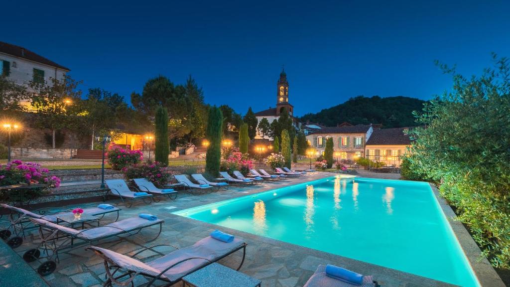 une piscine avec des chaises et une tour d'horloge en arrière-plan dans l'établissement Villa La Romantica 14, Emma Villas, à Grognardo