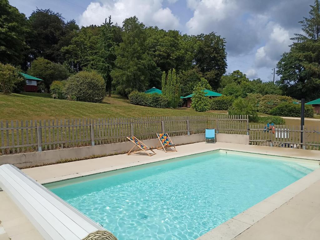 une piscine avec deux chaises et une clôture dans l'établissement Les cabanes de l'île aux oiseaux Guern, à Guern