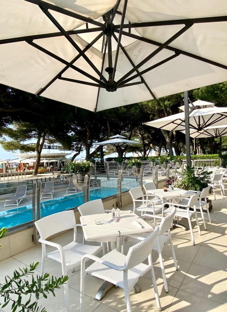 un groupe de tables et de parasols à côté d'une piscine dans l'établissement Grand Hotel Playa, à Lignano Sabbiadoro