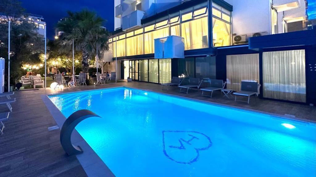 une piscine devant un immeuble la nuit dans l'établissement Hotel Aristeo, à Rimini