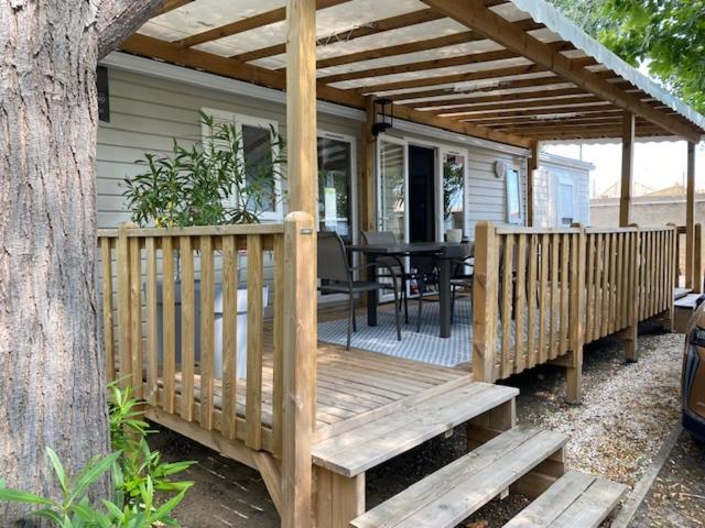 une terrasse en bois avec une table sur une maison dans l'établissement Mobil-Home - Les Terrasses Vias Plage, à Vias