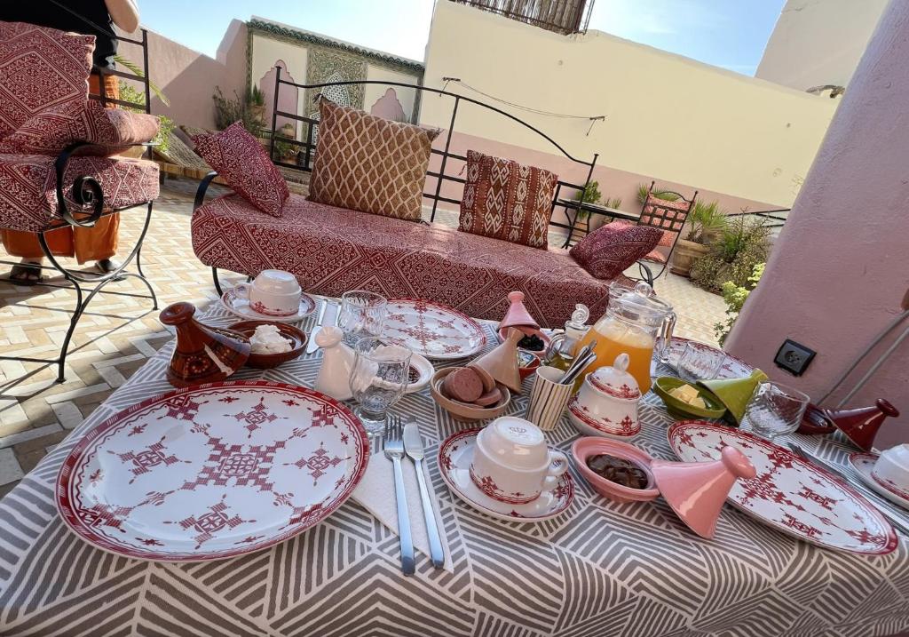 une table avec des assiettes et des ustensiles rouges et blancs dans l'établissement Riad Dezayn, à Fès 37 autres photos