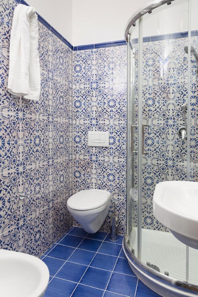 La salle de bains bleue et blanche est pourvue de toilettes et d'une douche. dans l'établissement Hotel Villa Nefele, à Giardini Naxos
