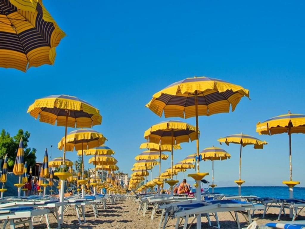 un groupe de parasols jaunes sur une plage dans l'établissement Hotel Villa Nefele, à Giardini Naxos