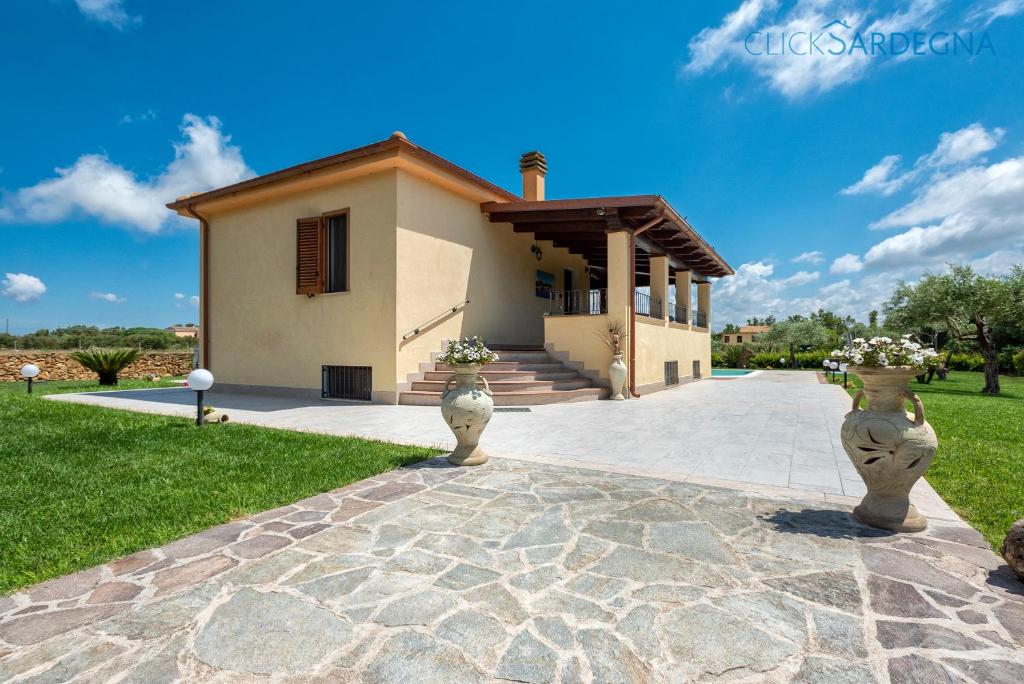une maison avec deux vases devant dans l'établissement Alghero Villa Marlena with pool for exclusive use for 10 people, à Alghero