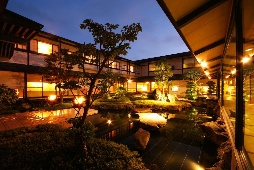 un hôtel avec un étang devant un bâtiment dans l'établissement Onishiya Suishoen, à Toyooka