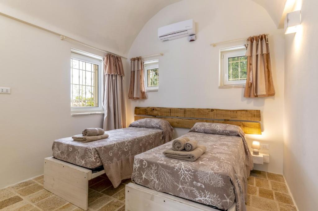 une chambre avec deux lits et deux fenêtres dans l'établissement Villa Trullo Oro Verde by Villa Plus, à Ostuni