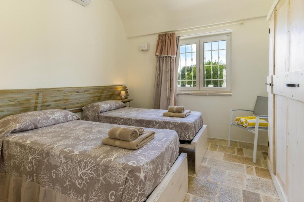 une chambre avec deux lits et une fenêtre dans l'établissement Villa Trullo Oro Verde by Villa Plus, à Ostuni