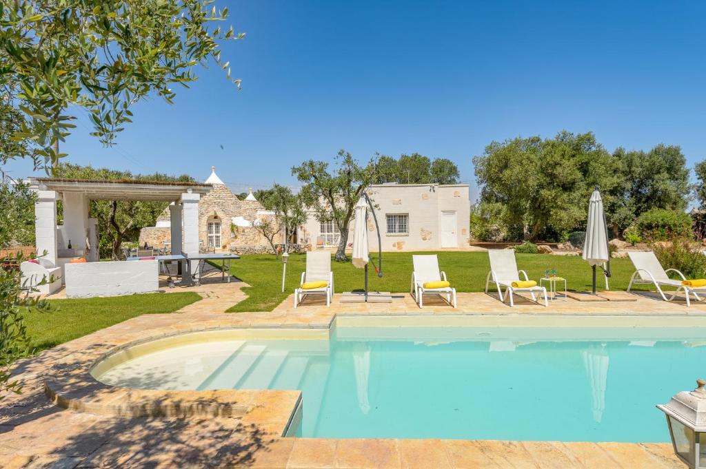 une piscine avec chaises et parasols dans une cour dans l'établissement Villa Trullo Oro Verde by Villa Plus, à Ostuni