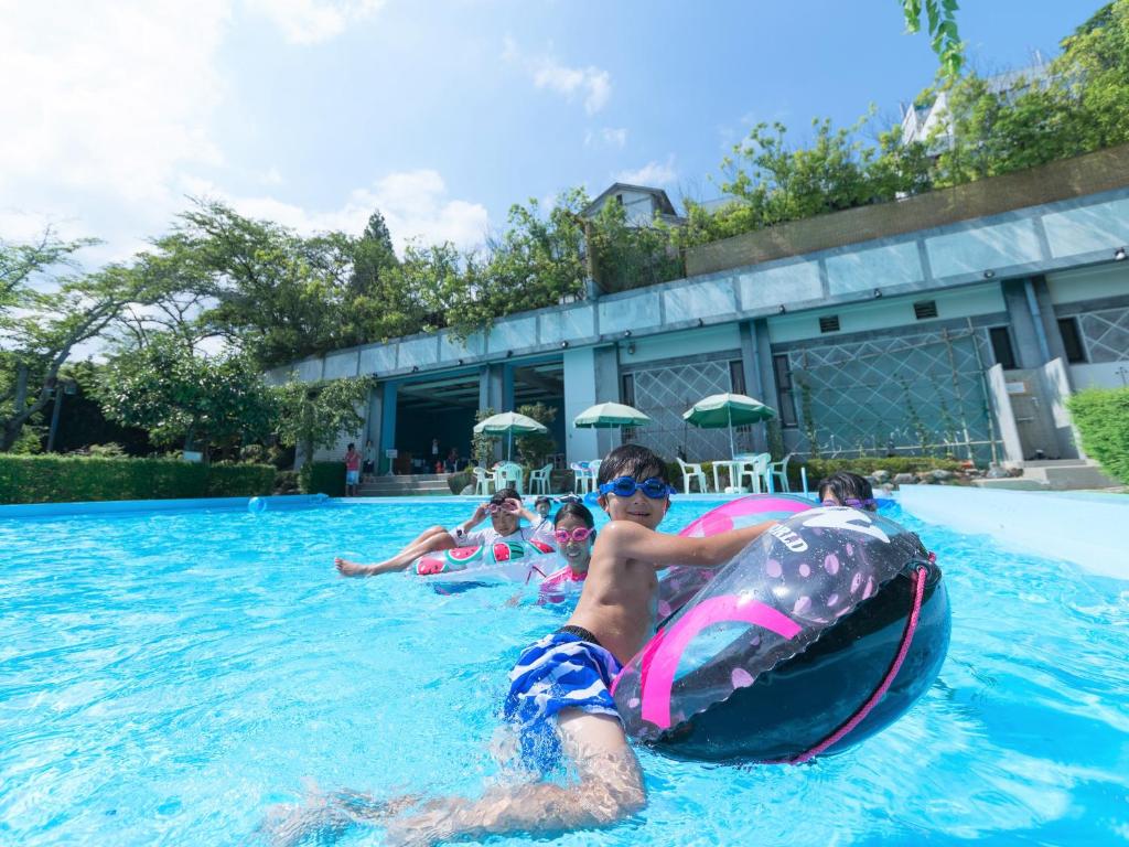 un groupe d'enfants sur une chambre à air dans une piscine dans l'établissement Yuzanso, à Ōtsu
