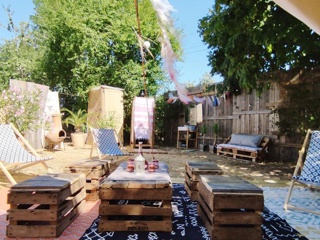 un patio avec une table, des chaises et des bûches dans l'établissement Le Bivouac, à Cabariot