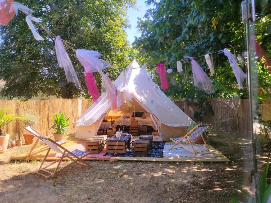 une tente dans une cour arrière avec des chaises et des tables dans l'établissement Le Bivouac, à Cabariot 2 autres photos