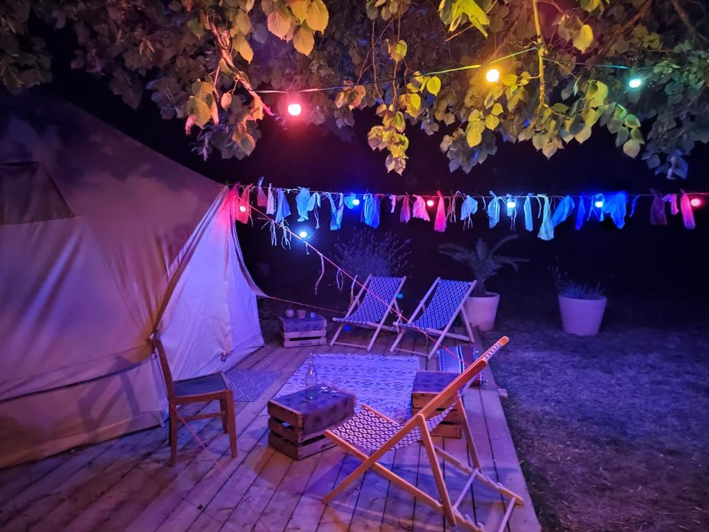 - un groupe de chaises assises sous une tente la nuit dans l'établissement Le Bivouac, à Cabariot