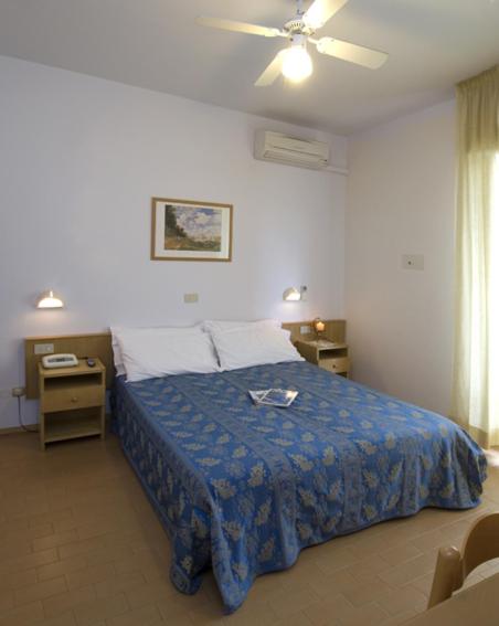 une chambre avec un lit et un ventilateur de plafond dans l'établissement Hotel Nives, à Riccione