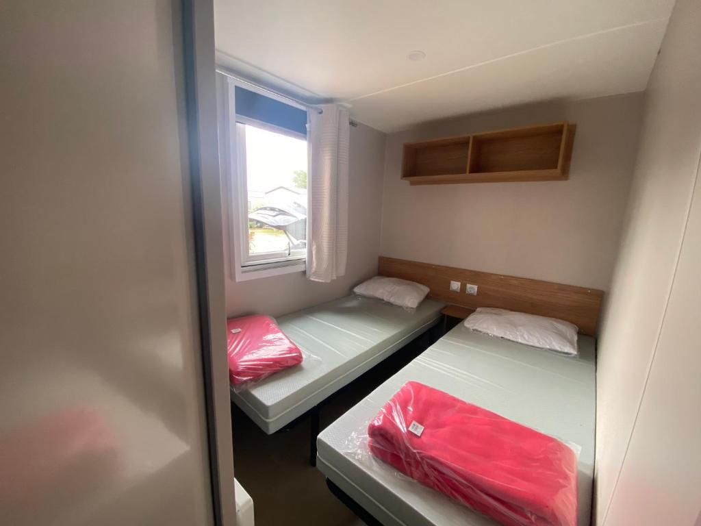 deux lits dans une petite pièce avec une fenêtre dans l'établissement Mobil-home - 8 pers - 100m des plages - tout confort - Camping Siblu 4 étoiles, à Canet