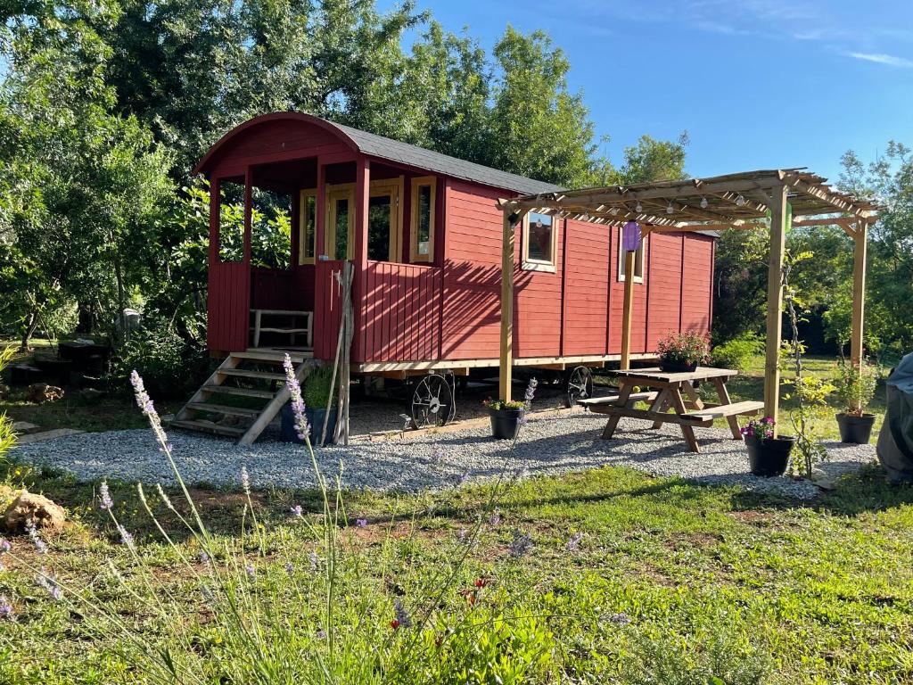 une petite maison rouge avec une table de pique-nique et une table de pique-nique dans l'établissement Roulotte , hébergement atypique, à Solliès-Pont