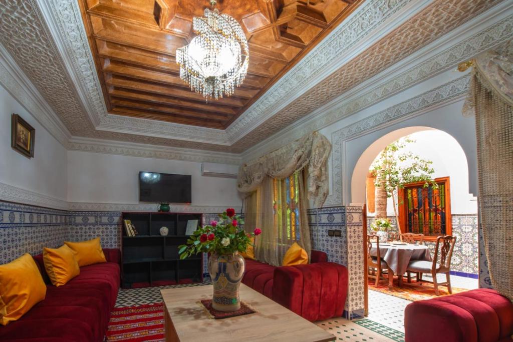 - un salon avec un canapé rouge et un lustre dans l'établissement Riad Amely, à Marrakech
