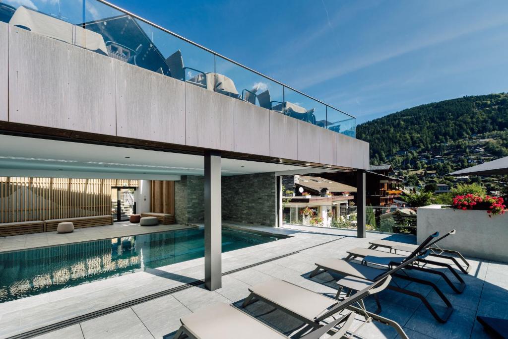 une maison avec une piscine et des chaises dans l'établissement Hôtel Champs Fleuris Morzine, à Morzine