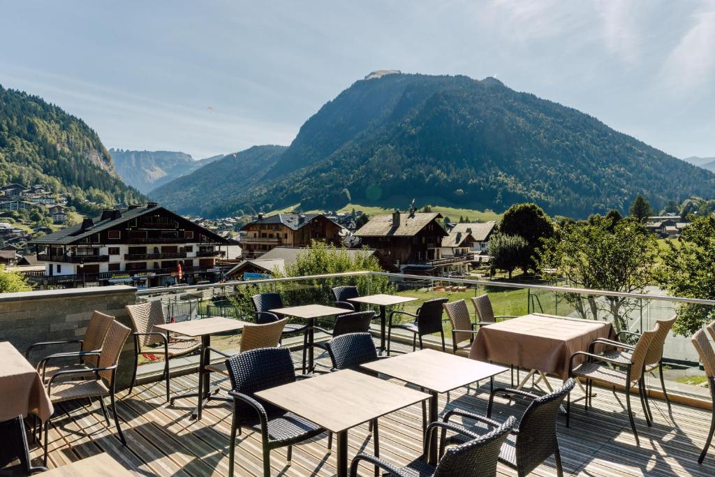 d'un balcon avec des tables, des chaises et des montagnes. dans l'établissement Hôtel Champs Fleuris Morzine, à Morzine
