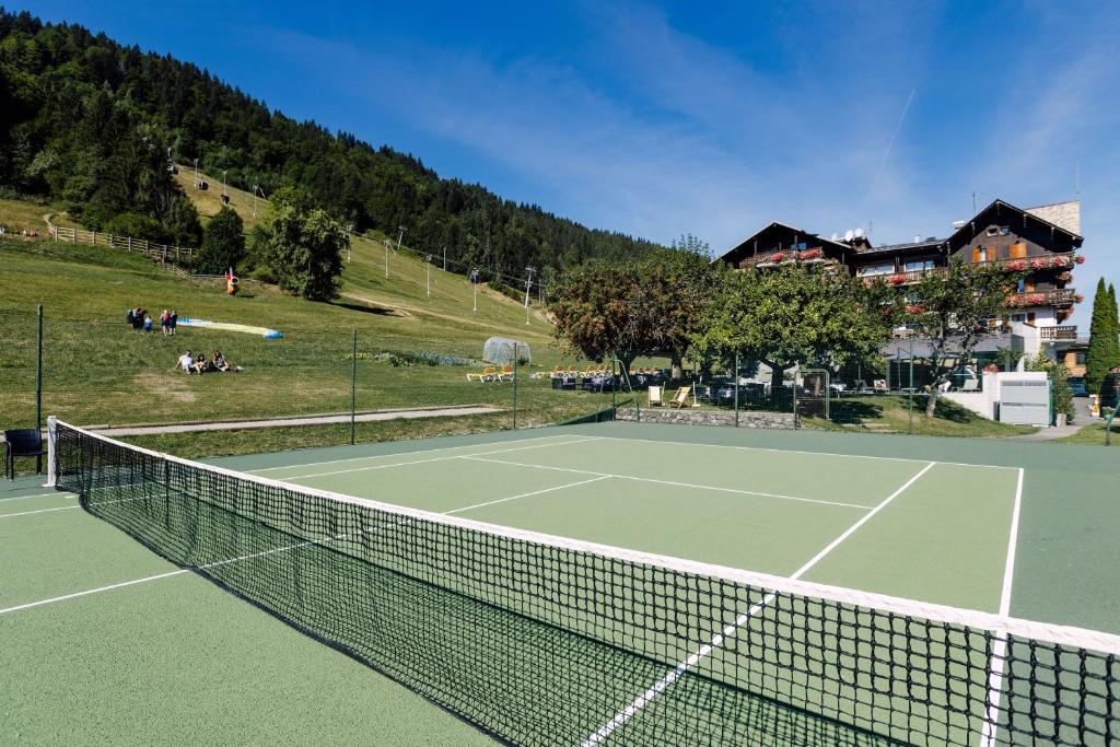 - un filet de tennis sur un court de tennis en face d'une maison dans l'établissement Hôtel Champs Fleuris Morzine, à Morzine