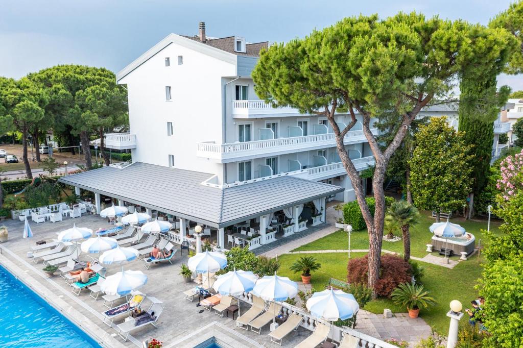 - une vue aérienne sur un hôtel avec des chaises et des parasols dans l'établissement Hotel Al Cigno, à Lignano Sabbiadoro