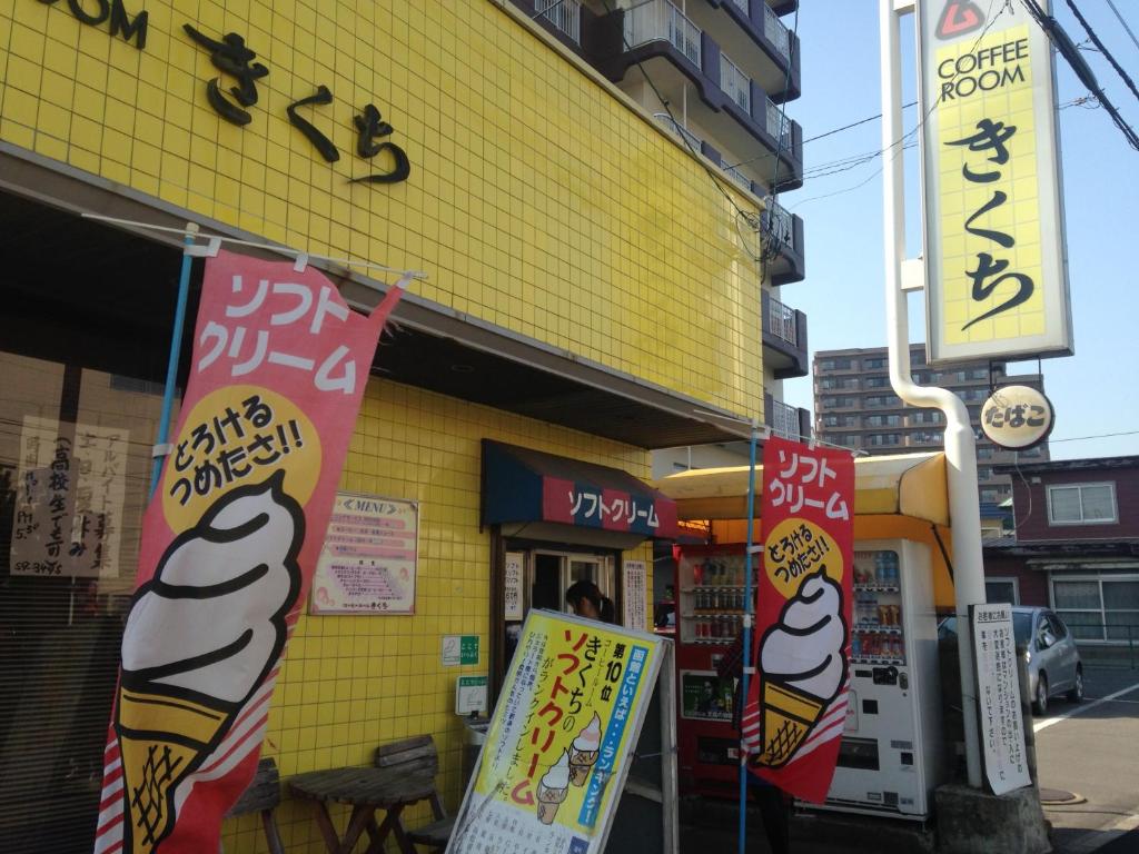 un bâtiment jaune avec des panneaux devant lui dans l'établissement Hotel Tetora Yunokawaonsen, à Hakodate