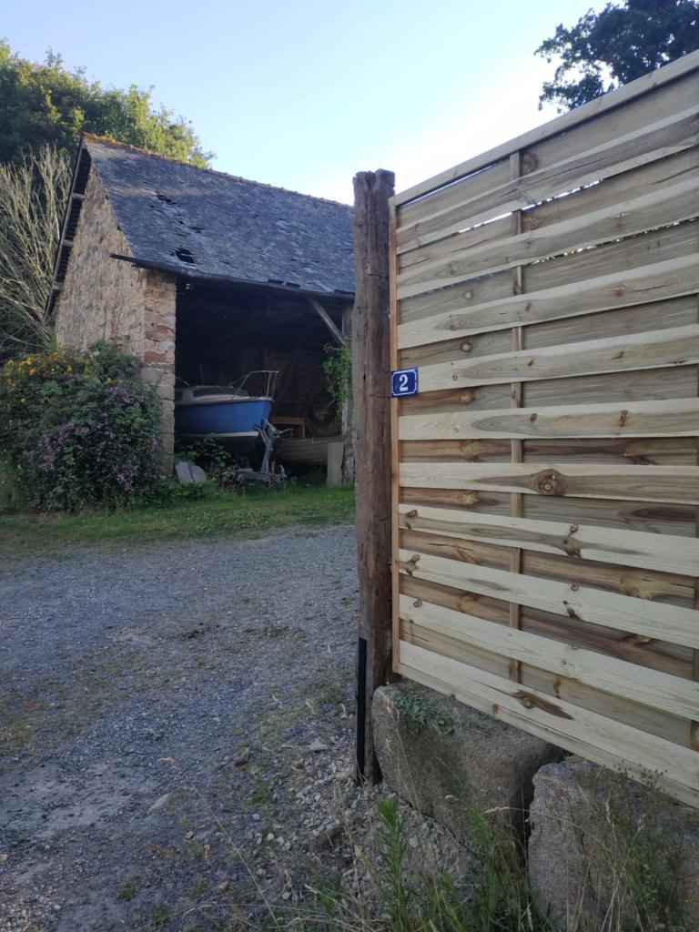 une clôture en bois devant une grange dans l'établissement Edel de la Touche Balard, à Val Couesnon