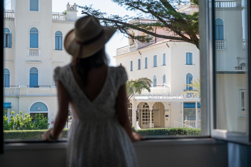une femme en robe blanche et chapeau donnant sur une fenêtre dans l'établissement La Dépendance by Casa Bianca, à Lido di Jesolo