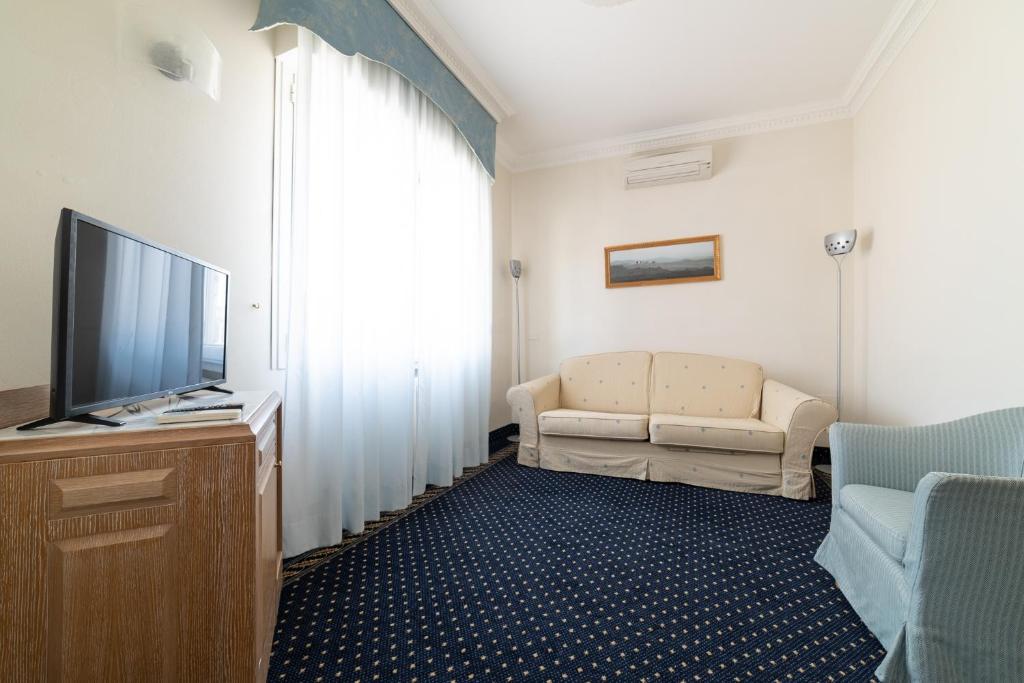 un salon avec un canapé et une télévision dans l'établissement La Dépendance by Casa Bianca, à Lido di Jesolo