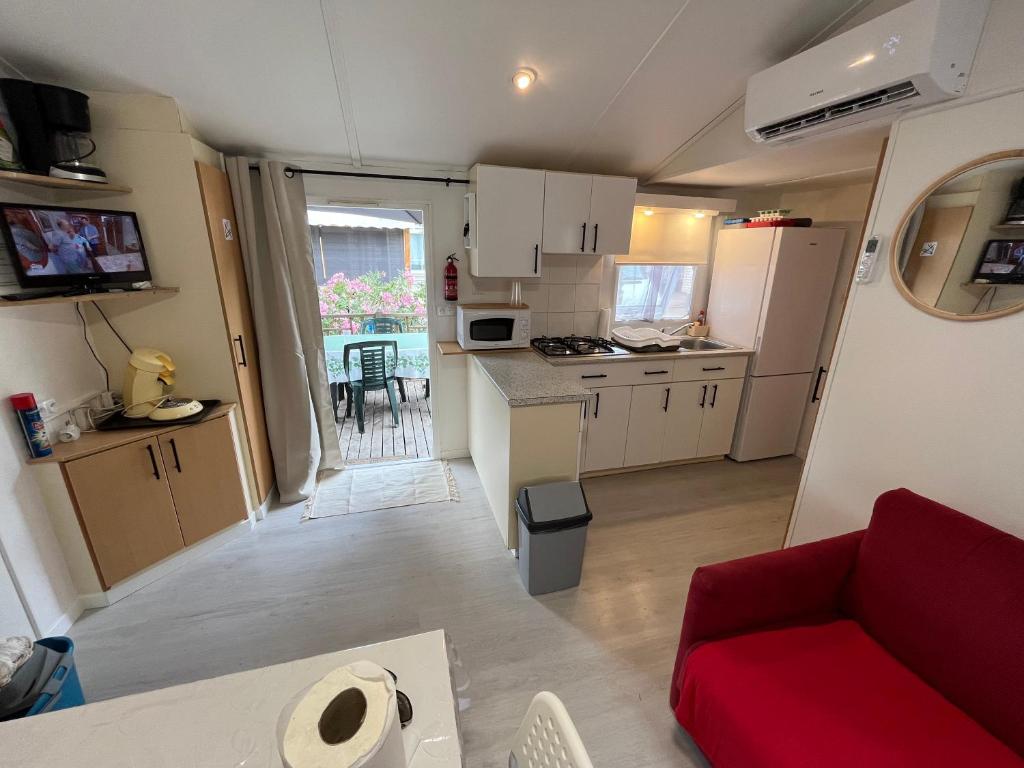 Il comprend une petite cuisine et un salon avec un canapé rouge. dans l'établissement Mobile home camping Pedro, au Grau-dʼAgde