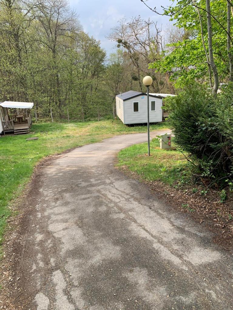 un chemin de terre menant à une petite remorque blanche dans l'établissement Mobil-home ( dépaysement total à 40 km de paris ), à Saint-Chéron