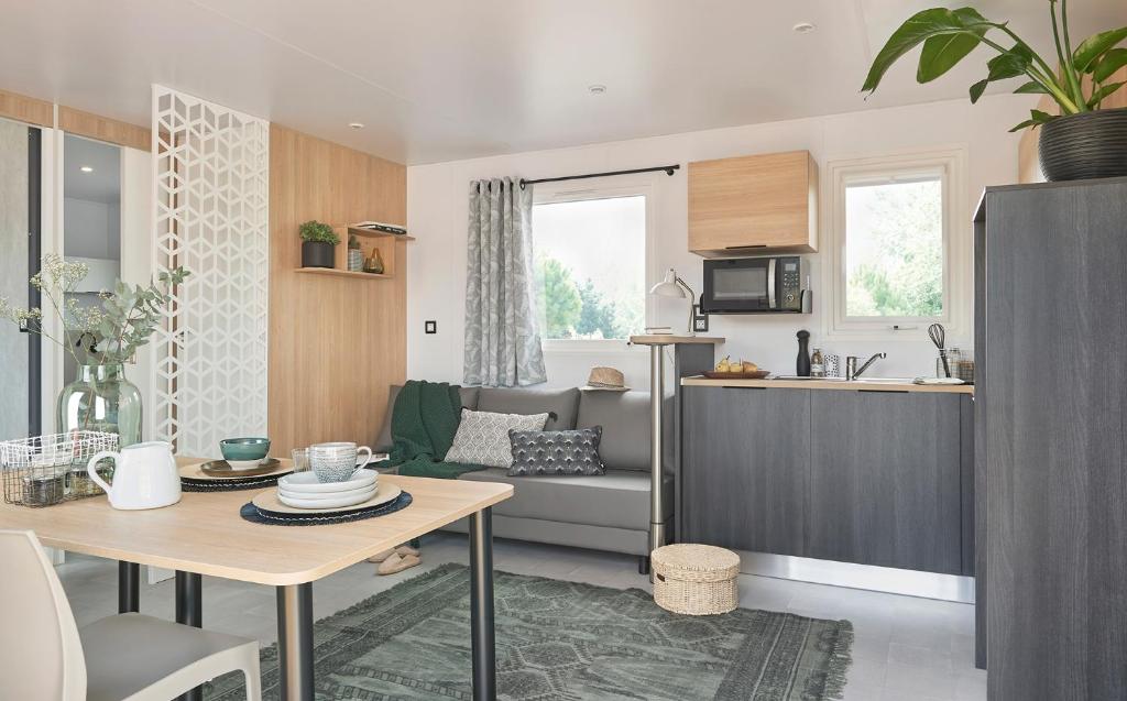 une cuisine et un salon avec un canapé et une table dans l'établissement Camping Le Village de la Mer, à Les Moutiers