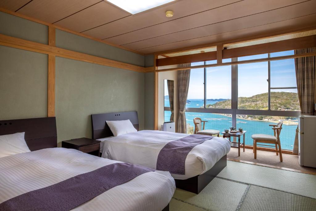 deux lits dans une chambre avec vue sur l'océan dans l'établissement Ama no Shima, à Toba