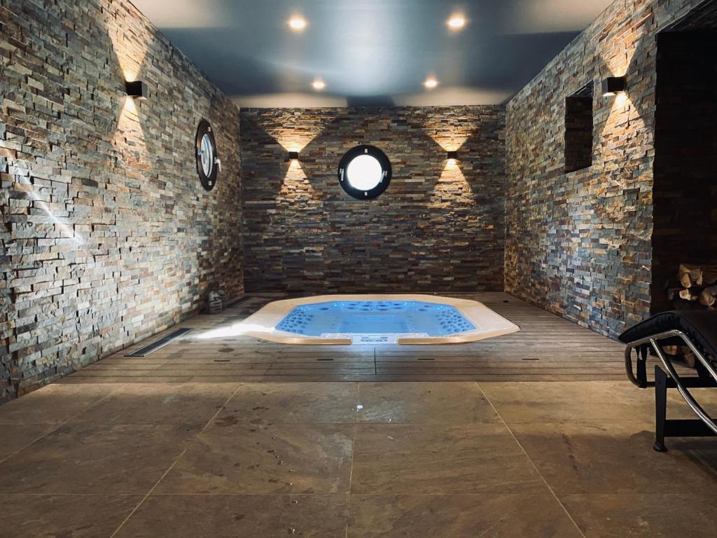 Cette chambre dispose d'un bain à remous dans un mur en briques. dans l'établissement Hôtel 16 | 150 Montagne & Spa Nuxe, à Vars