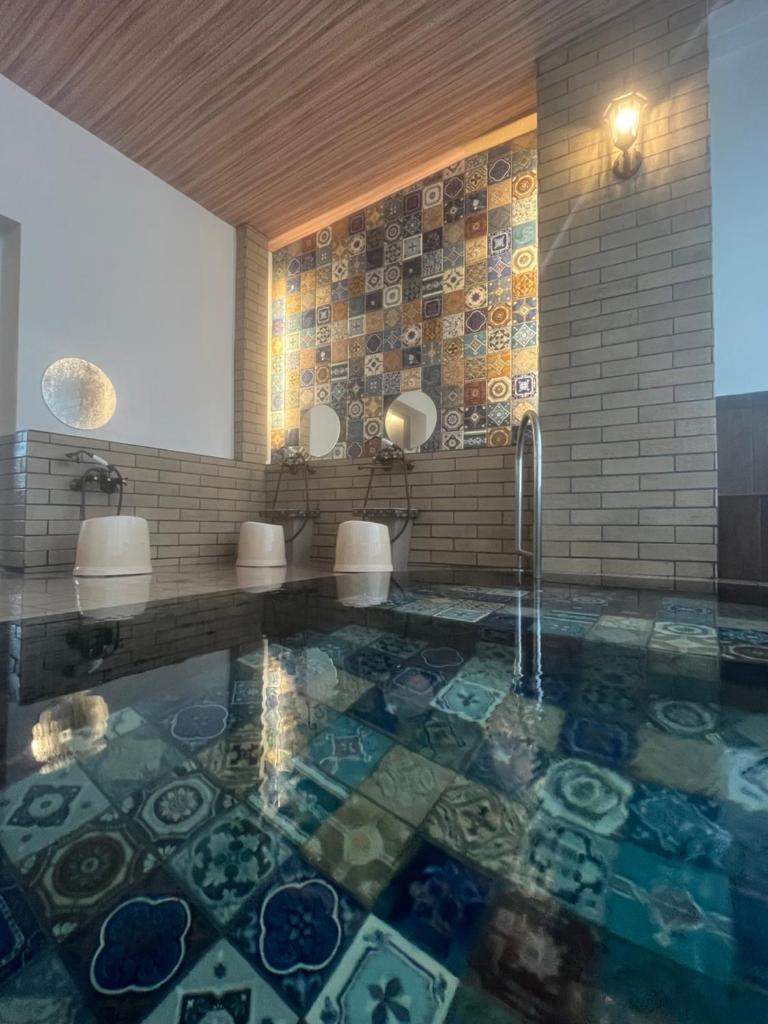 La salle de bains est pourvue d'une baignoire et d'un sol en mosaïque. dans l'établissement Historical Ryokan SENYUKAN, à Ōwani