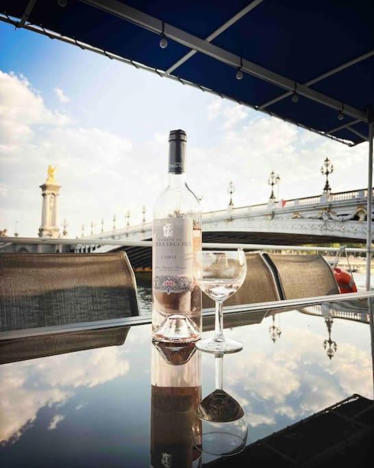 - une bouteille de vin et un verre assis sur une table dans l'établissement Péniche de charme au pont Alexandre III, à Paris