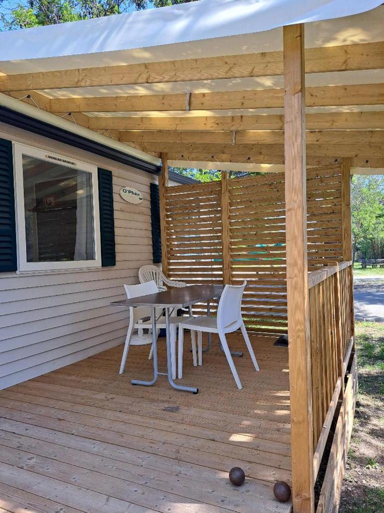 une terrasse en bois avec une table et des chaises dessus dans l'établissement Mobil Home Domaine des Iscles, à La Roque-dʼAnthéron
