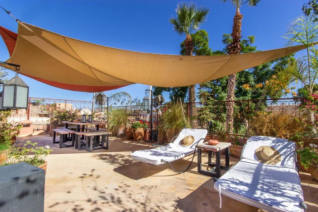 d'une terrasse avec un auvent, des chaises et des tables. dans l'établissement Riad Dar Al Barakaa - EXCLUSIVE - Breakfast, à Marrakech