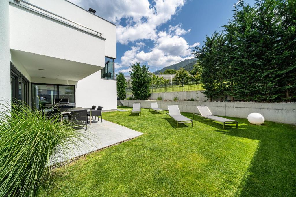 une cour avec des chaises, une table et de la pelouse dans l'établissement Villa Shangrila, à Naturno