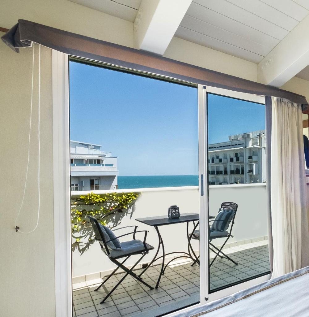 un balcon avec une table et des chaises et une vue sur l'océan dans l'établissement Hotel Maestrale, à Riccione
