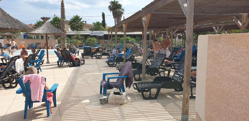 un groupe de personnes assises sur une terrasse avec des chaises dans l'établissement camping les sables du midi, à Sérignan