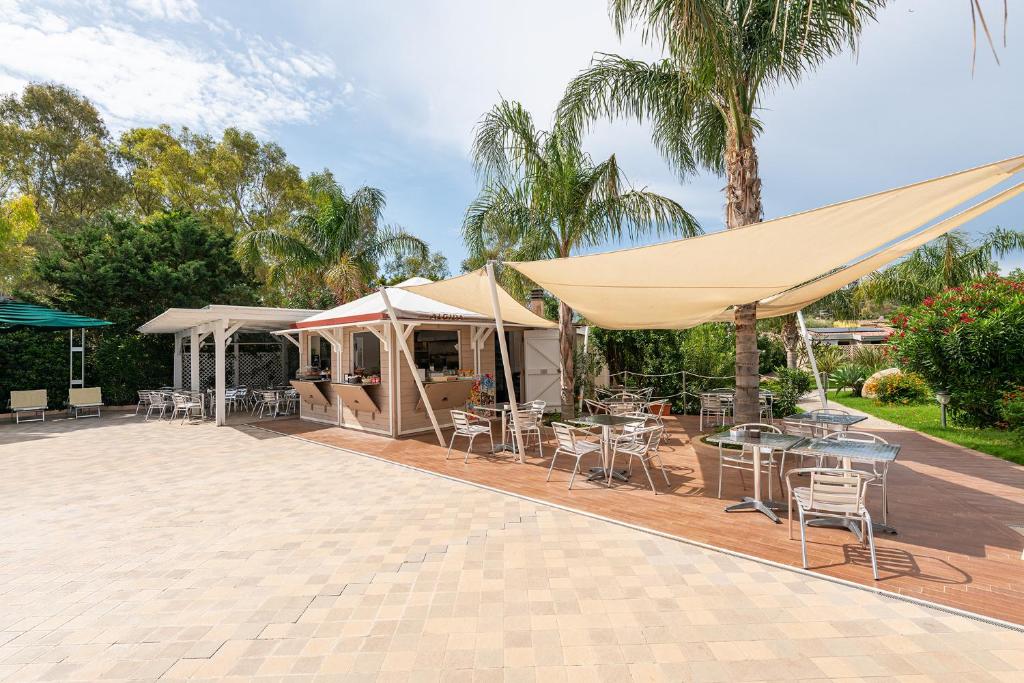 - un patio avec des tables et des chaises sous des tentes dans l'établissement Green Village Resort, à Villasimius