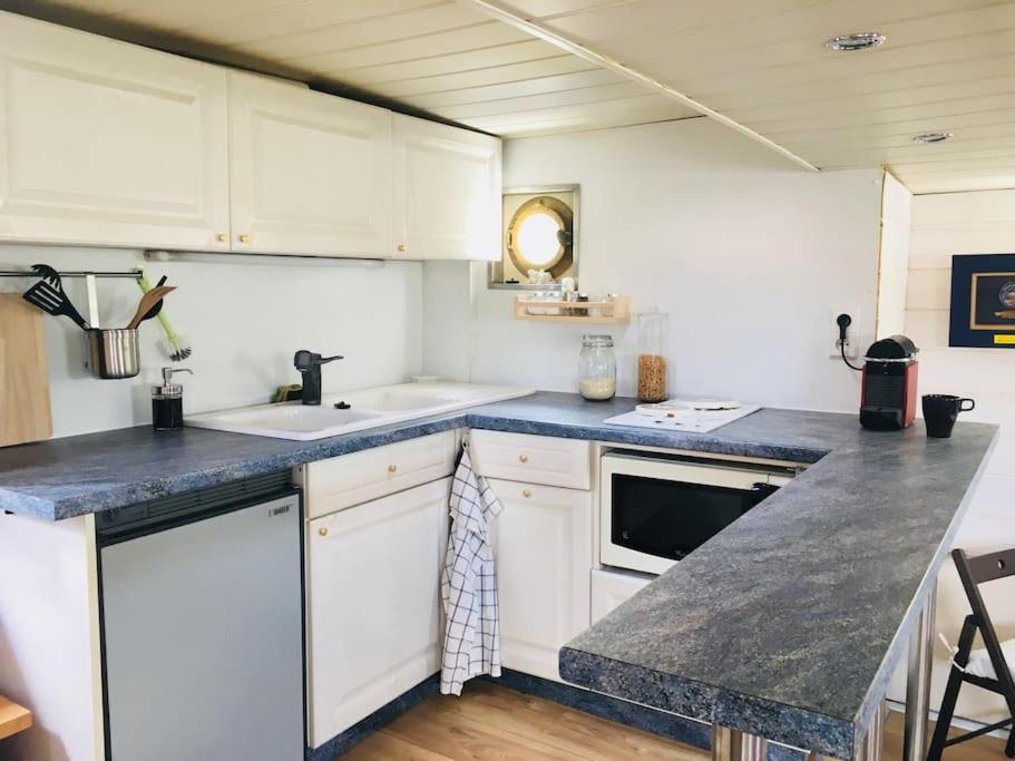 une cuisine avec des placards blancs et un comptoir bleu dans l'établissement Captain's cabin: Cosy flat on a house boat, à Strasbourg