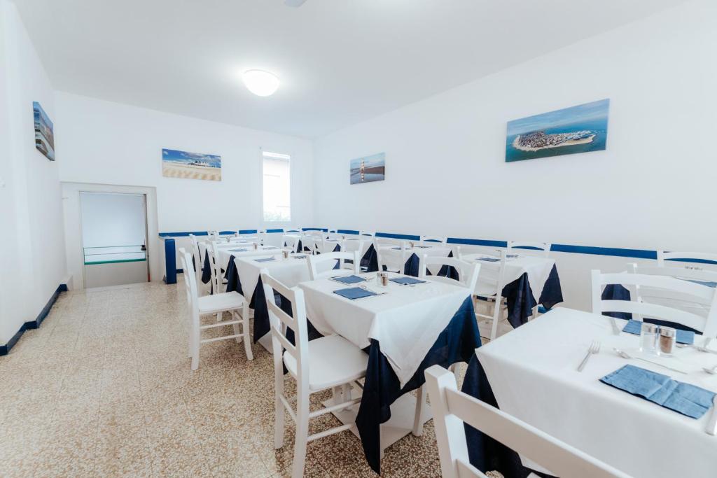 une salle à manger avec des tables blanches et des chaises blanches dans l'établissement Hotel Villa Franca, à Lignano Sabbiadoro
