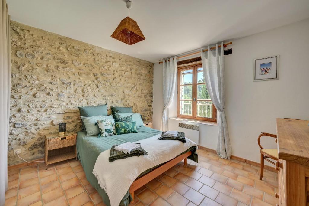 une chambre avec un lit et un mur en pierre dans l'établissement Domaine Bellavigne Gites et SPA, à Forcalquier 37 autres photos