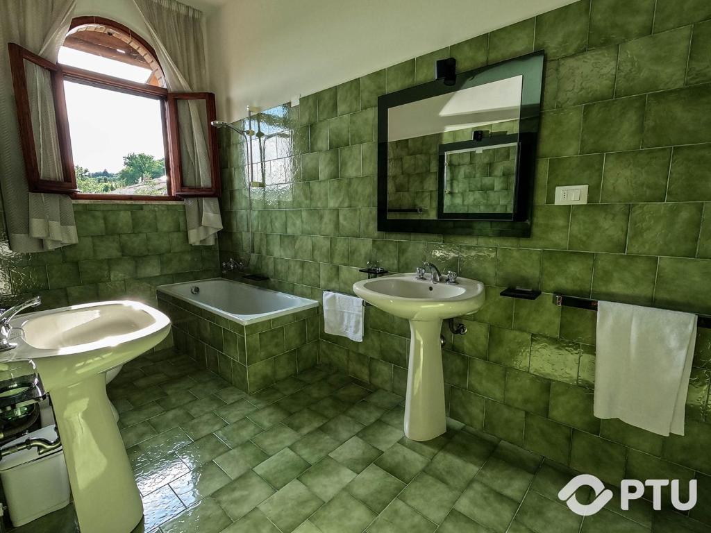 La salle de bains carrelée de couleur verte est pourvue d'un lavabo et d'une baignoire. dans l'établissement PoloTuristicoUmbria Villa del Maestrale, à Pérouse 34 autres photos