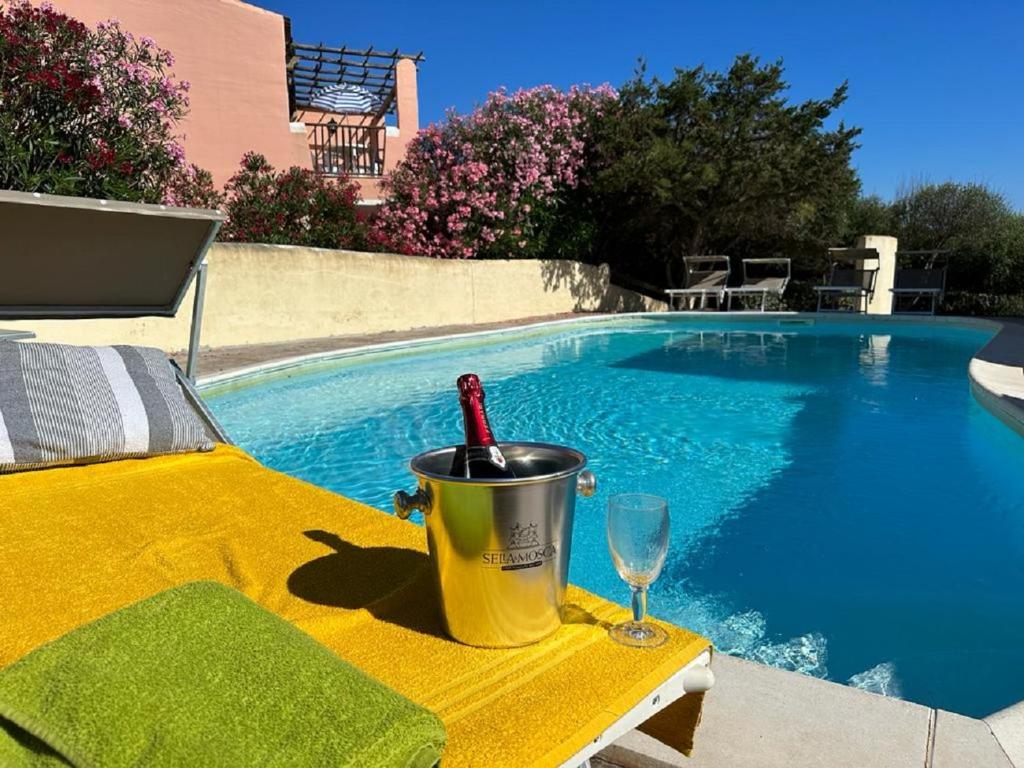 - une table avec une bouteille de vin et un verre à côté de la piscine dans l'établissement Eduard Villa, à Stintino