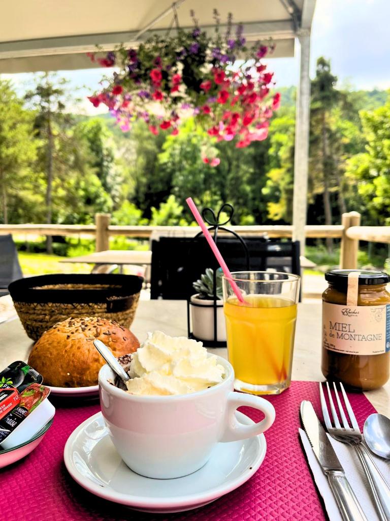 - une table avec un bol de nourriture et une tasse de jus d'orange dans l'établissement Village de chalets et camping La Pierre de l'Aigle, à La Bréole